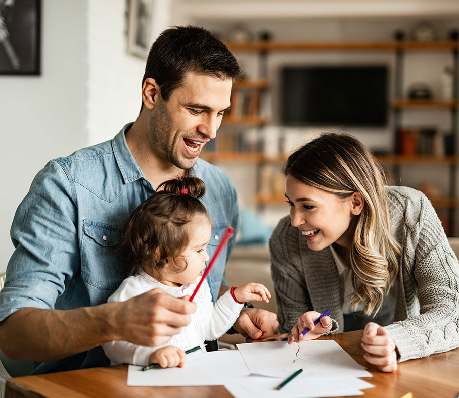 Happy parents and their small daughter having fun while coloring